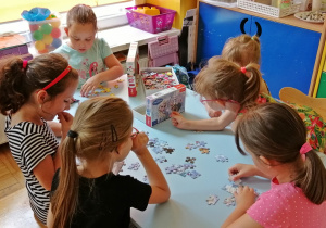 Dzieci układają puzzle na stoliku